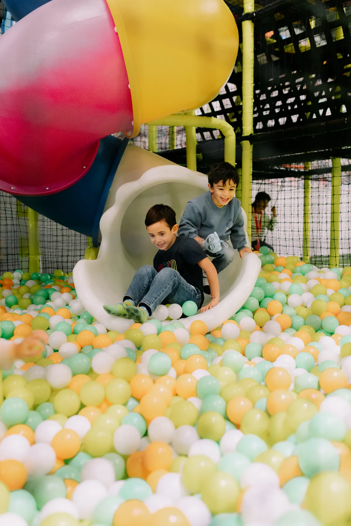 Crianças a deslizar para a piscina de bolas no parque Arena Kids